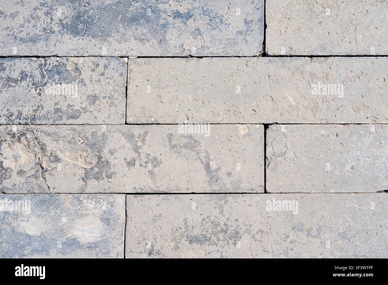 Light Gray Limestone Block Wall Texture Background with Weathered Natural Stone Pattern. Stock Photo