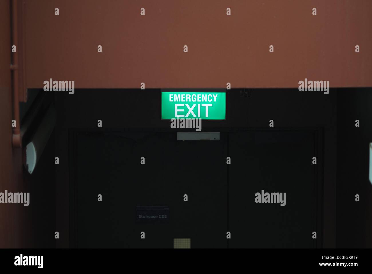 Emergency exit sign over dark door in hall Stock Photo