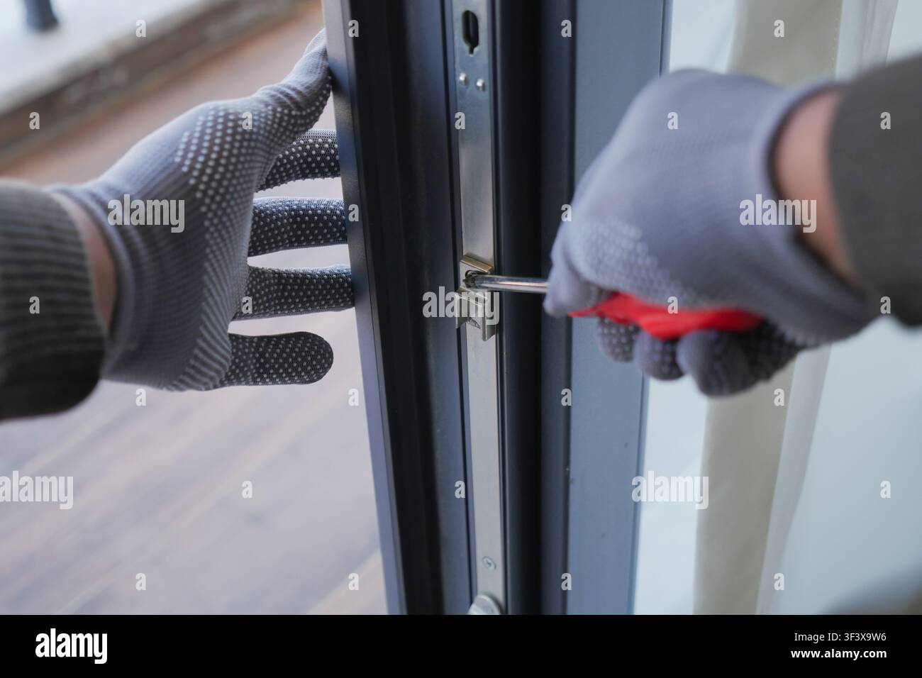 Person using screwdriver to unlock door Stock Photo