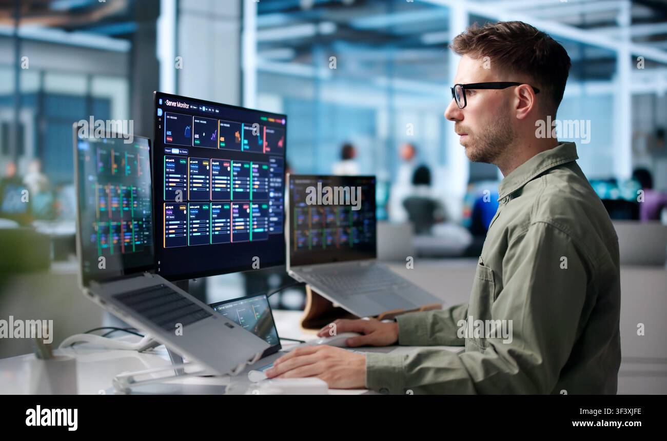 Young IT Specialist Monitors Real-time Network Performance Using Advanced Computer Tools. Stock Photo