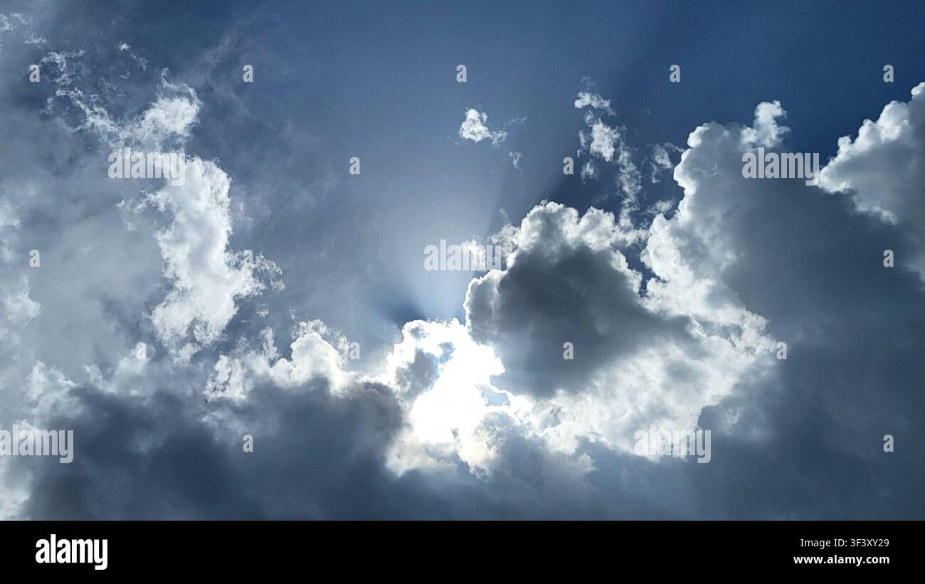 Dramatic Cloud Formation with Sunlight Breaking Through Against a Blue Sky Stock Photo