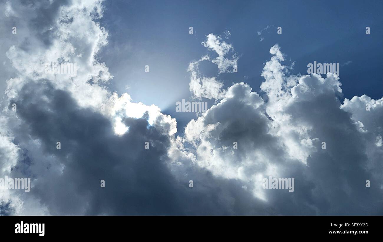 Dramatic Cloud Formation with Sunlight Breaking Through Against a Blue Sky Stock Photo