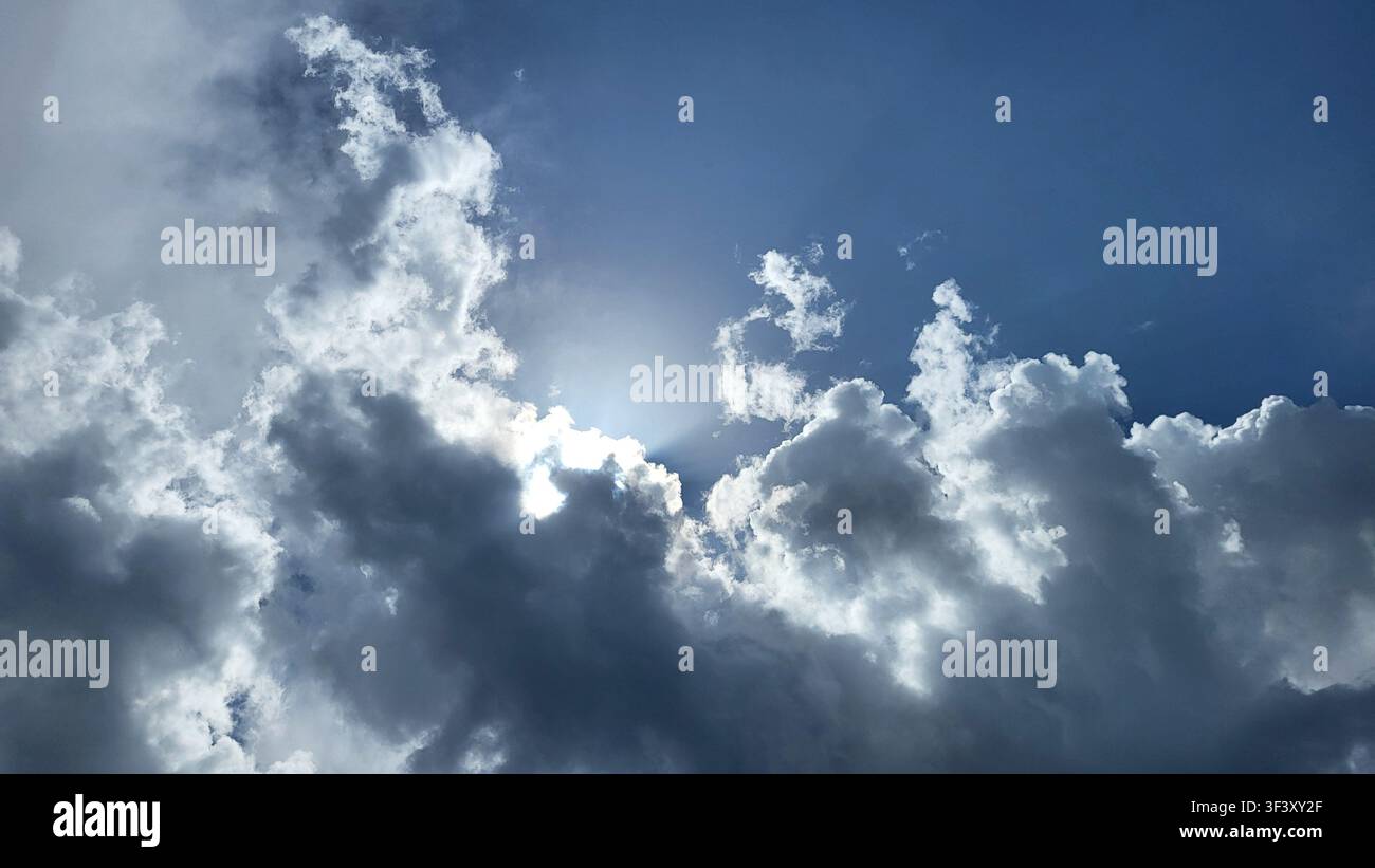 Dramatic Cloud Formation with Sunlight Breaking Through Against a Blue Sky Stock Photo