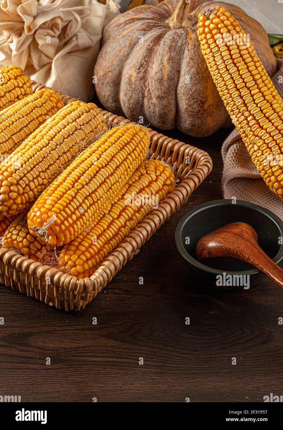 Dried yellow corn cobs arranged in a woven basket Stock Photo