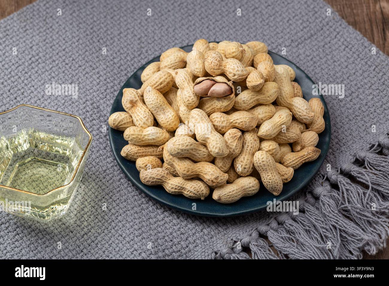 Roasted peanuts in shell served on blue dish Stock Photo