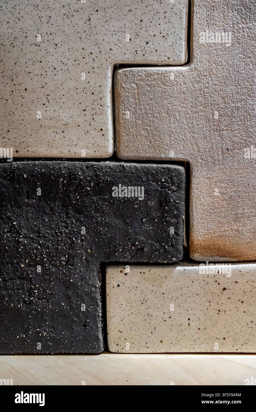 Close-up of textured ceramic tiles in staggered brick pattern, black beige and gray speckled glaze, minimalist wall design Stock Photo