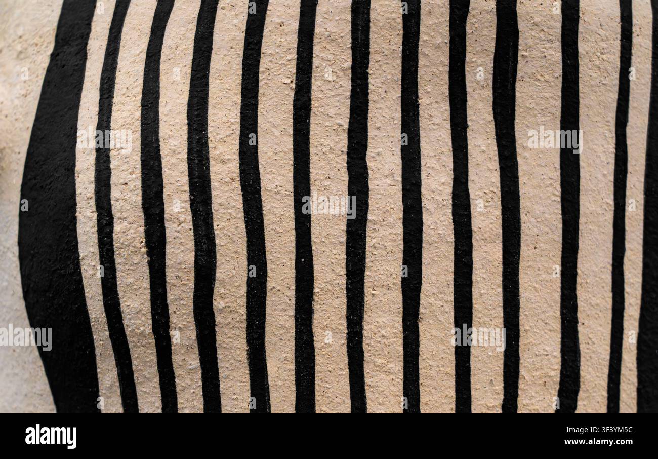 Close-up of hand-painted black vertical stripes on textured beige ceramic surface, minimalist pottery art, no people, abstract pattern Stock Photo