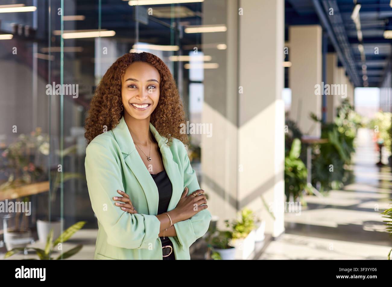 Professional manager in green blazer standing confident and smiling in office Stock Photo