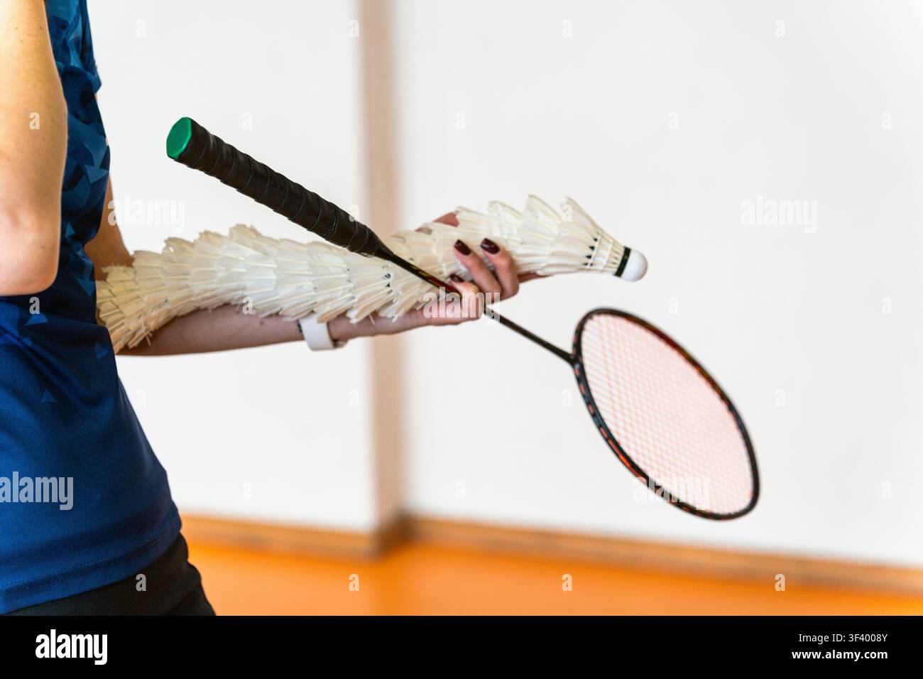 badminton coach holding feather shuttlecock stack and racket indoors Stock Photo