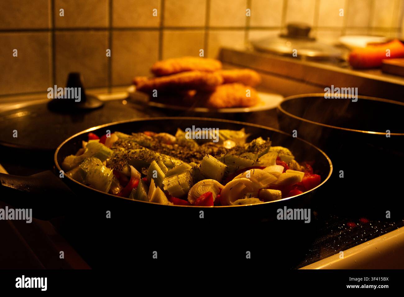 Chopped vegetables in a frying pan on a kitchen stove. Stock Photo