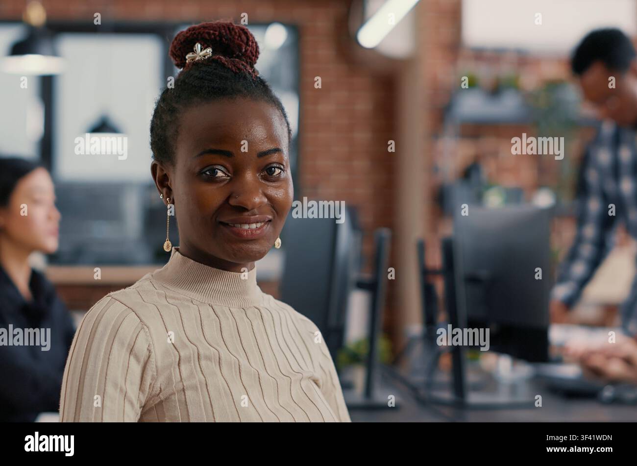 Focused portrait with smiling african american software developer looking at camera in artificial intelligence development agency around computer screens, showing developer teamwork, source code. Stock Photo