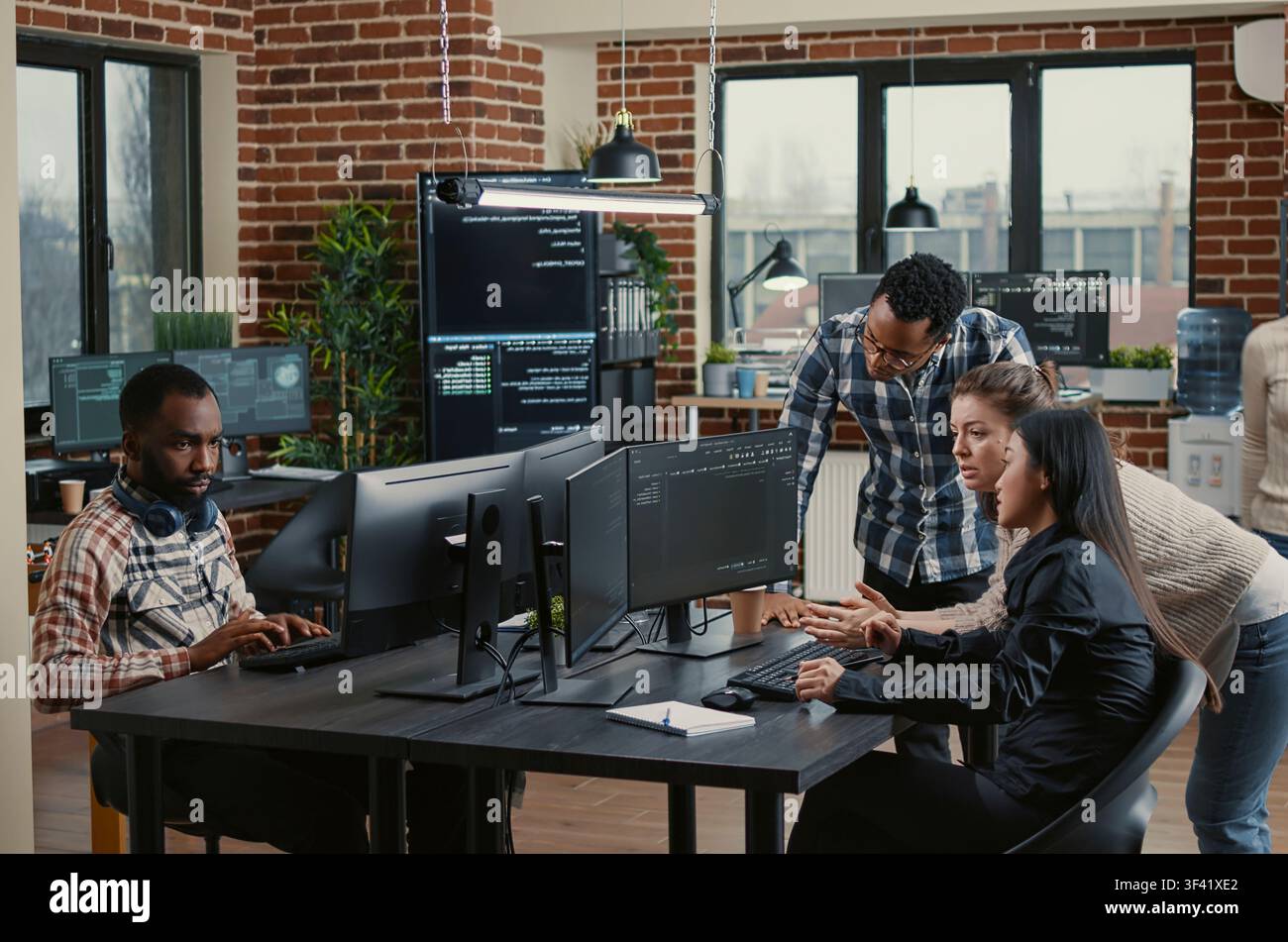 Junior programmers collaborating on software project compilation in a programming workspace, connecting source code, database logic and collaborative development for a technology project. Stock Photo