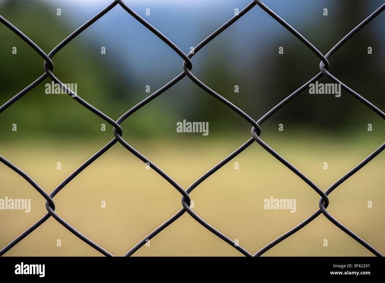 Chain link fence forms a metal grid pattern, creating a boundary Stock Photo