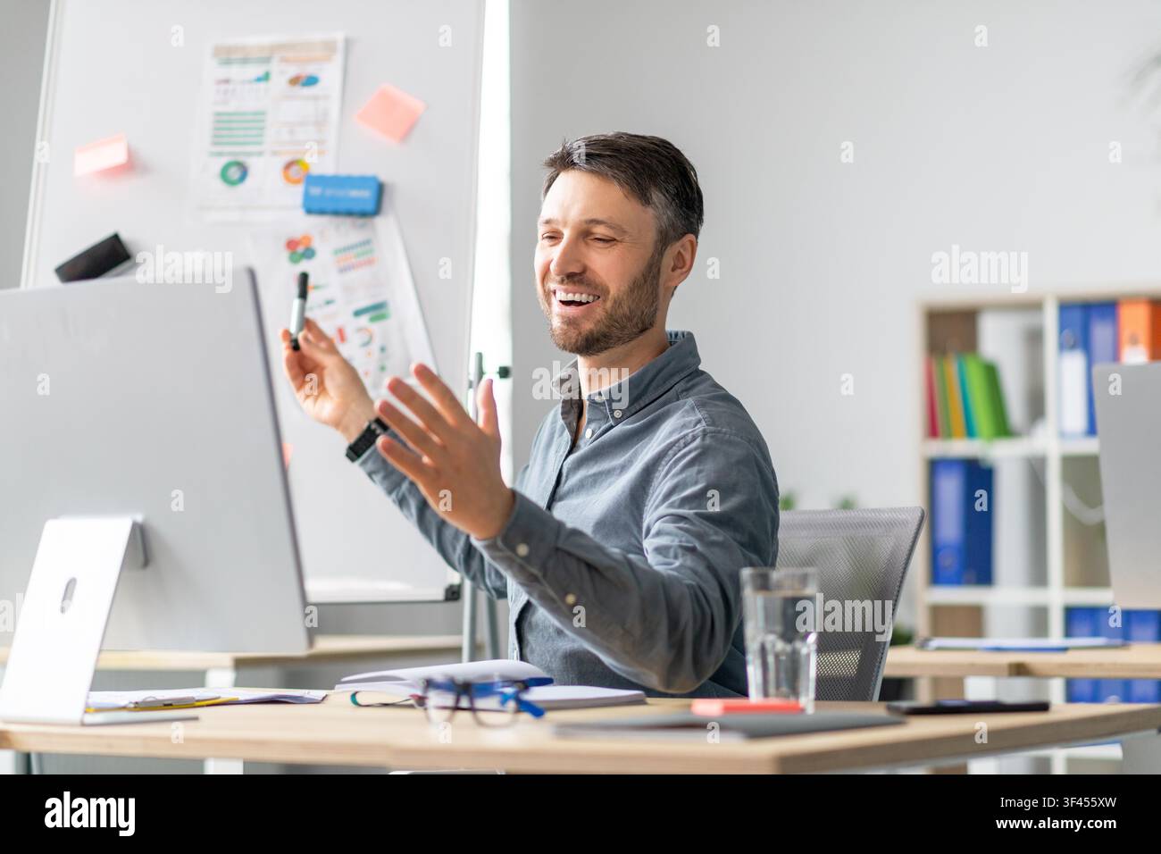 Smiling Caucasian Man Presenting Ideas At Desk In Office, Business Concept Stock Photo