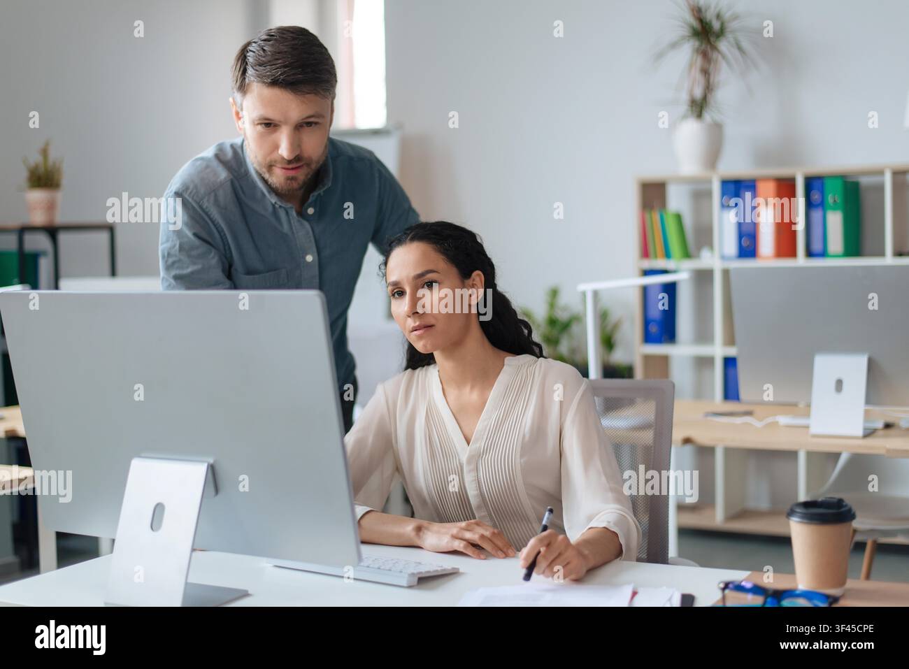 Business Professionals Collaborating In Office, Focused On Computer Screen Stock Photo