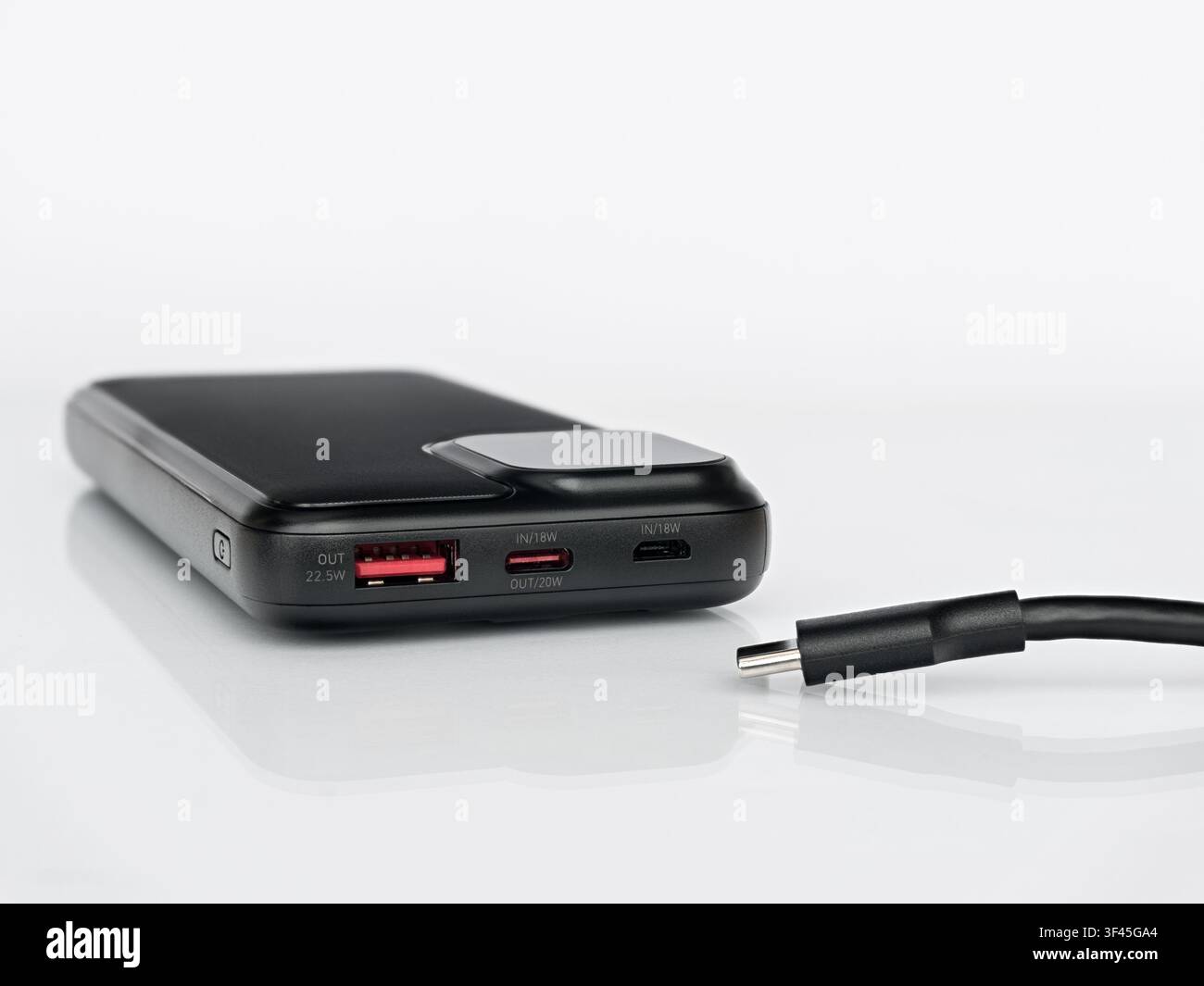 Black portable power bank with USB-C cable isolated on white background with reflection, external battery charger for smartphone Stock Photo