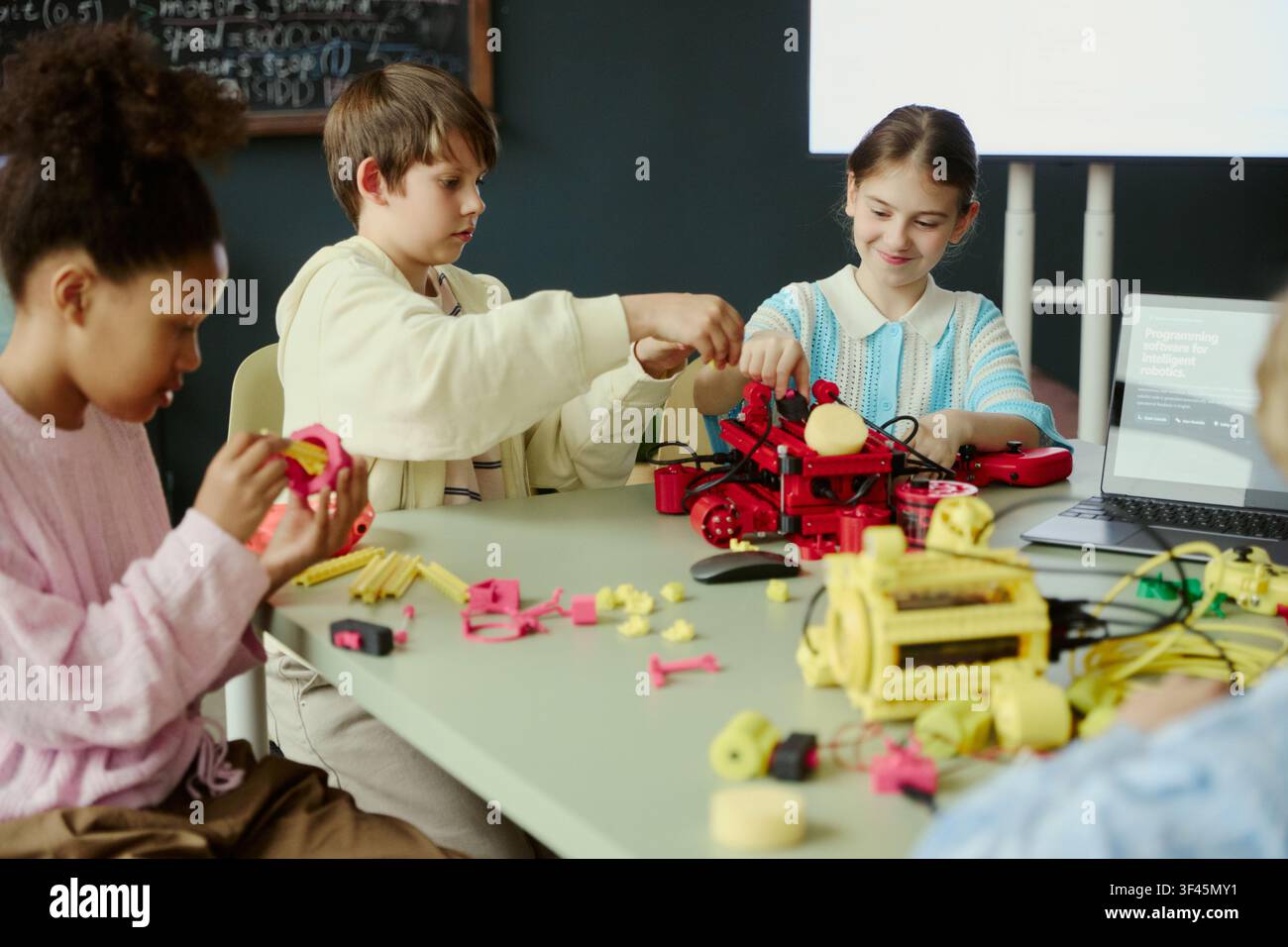 Diverse children assembling robotics models during classroom coding lesson, learning engineering teamwork and STEM skills. Ideal for education marketing, edtech promotion, STEM programs Stock Photo