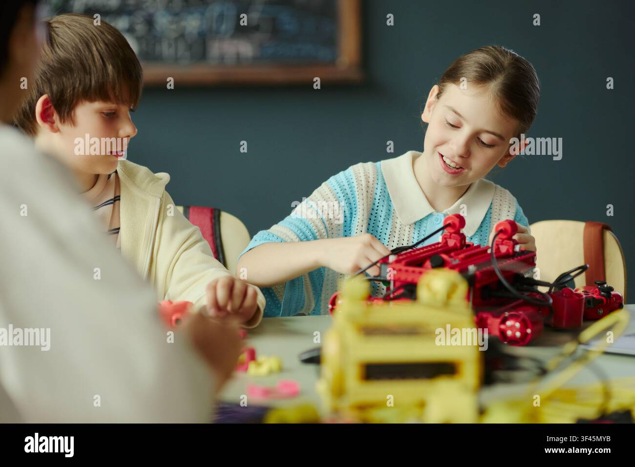School kids assembling robotics project during classroom STEM lesson, developing teamwork and engineering skills. Ideal for education marketing, coding courses, innovation programs Stock Photo