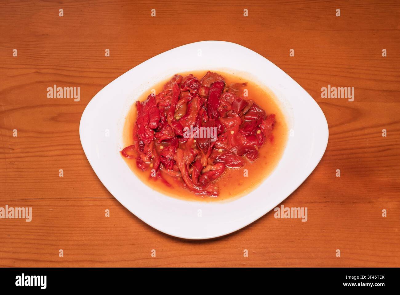 Roasted red pepper strips marinated in olive oil, plated on white square dish Stock Photo