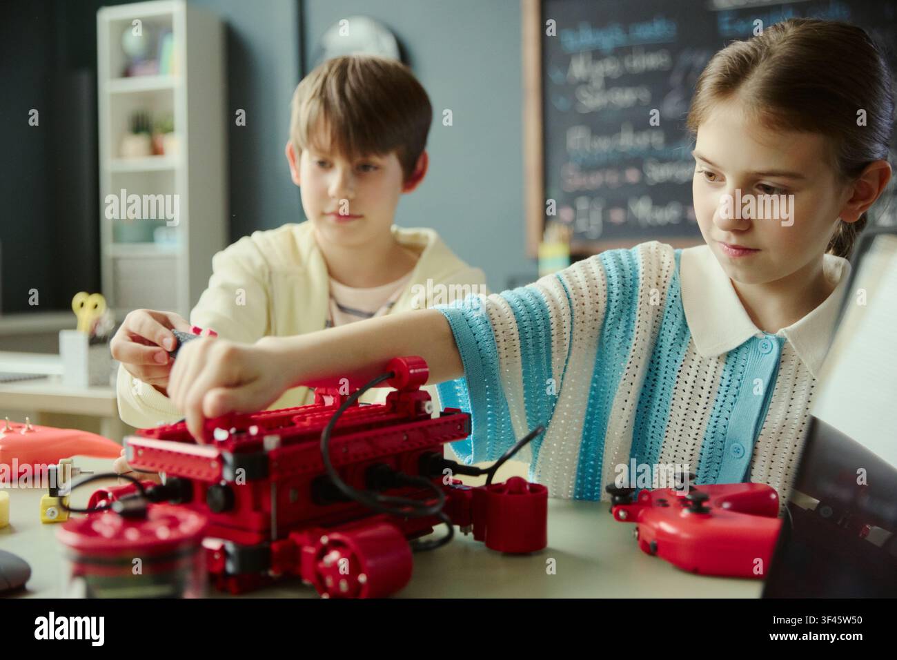 School kids assembling robotics project in classroom, learning engineering, coding, teamwork through hands on STEM activity. Ideal for education marketing, STEM programs, edtech promotion Stock Photo