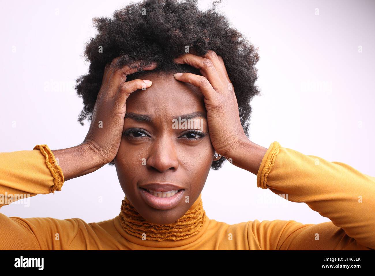 Stressed young black woman holding her head in frustration Stock Photo