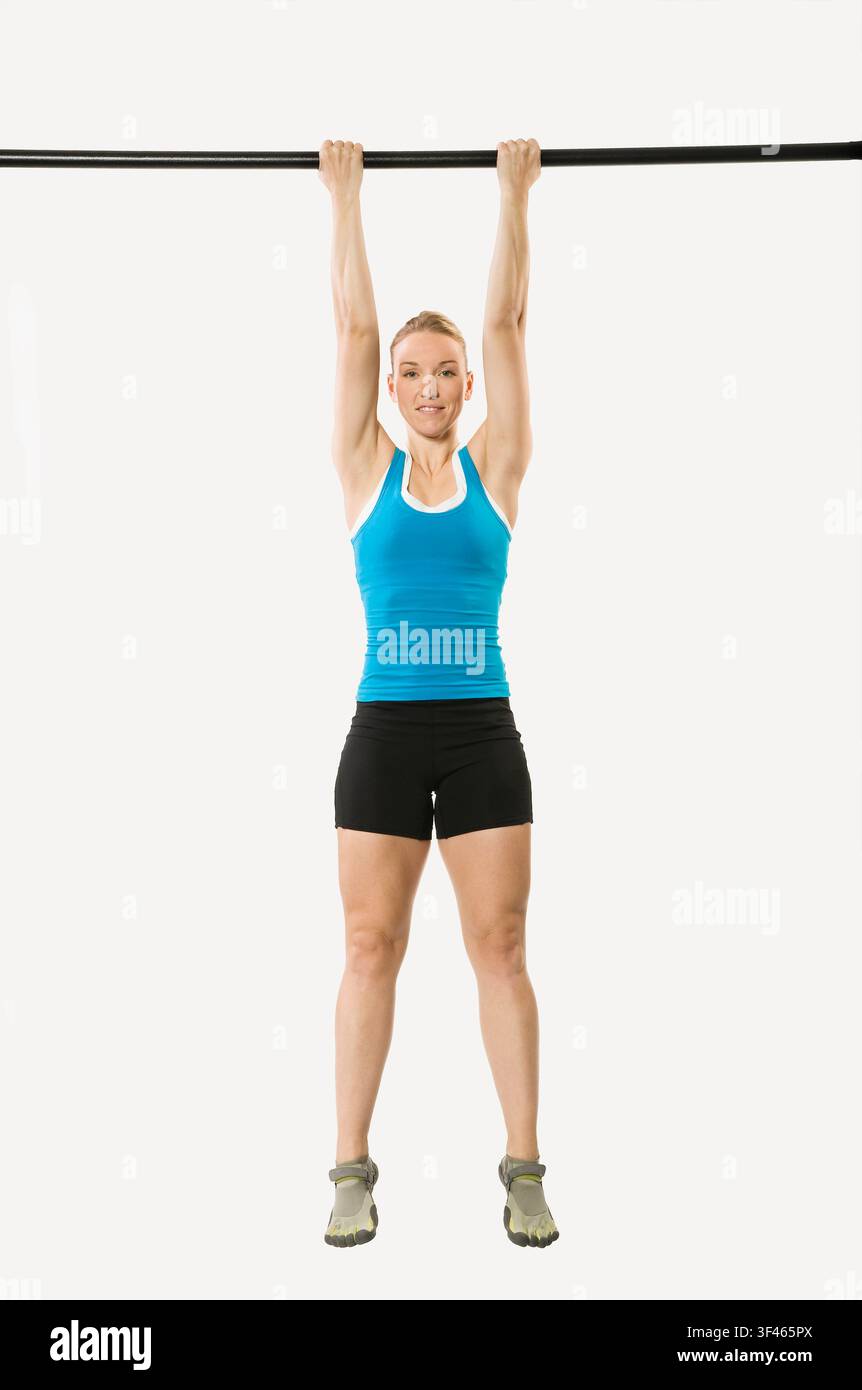Woman hanging from pull up bar smiling Stock Photo