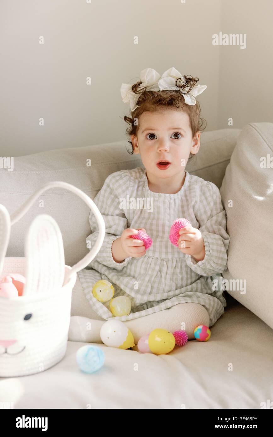 Surprised toddler discovers toys inside Easter eggs at home Stock Photo