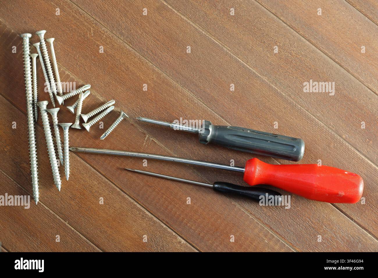 Screwdrivers and metal screws arranged on wooden surface with copy space Stock Photo