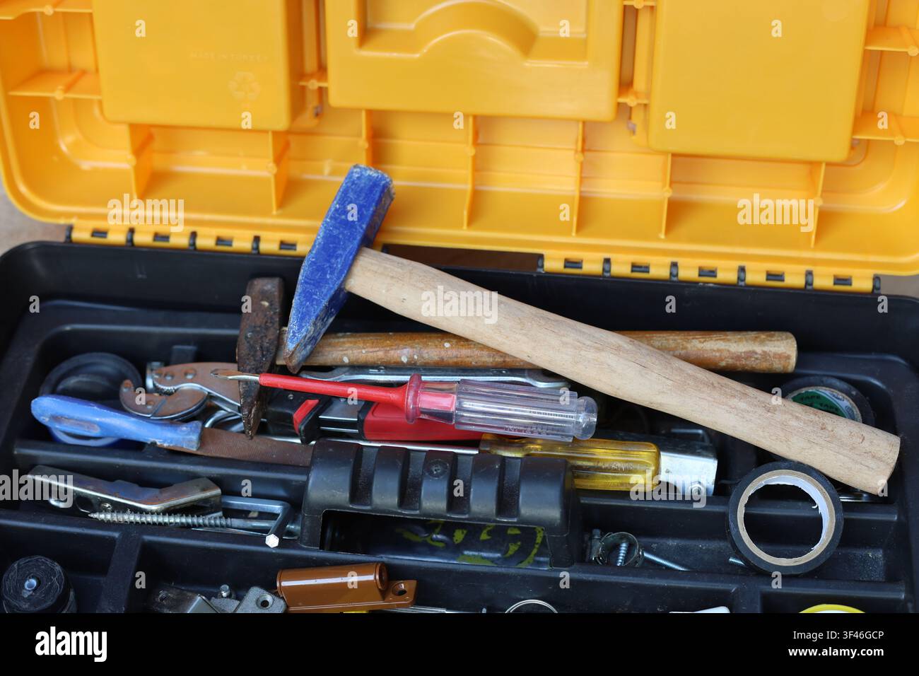 Open toolbox filled with various hand tools including hammer screwdriver and tape high angle view Stock Photo
