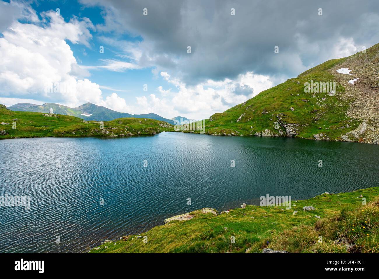 lake in romania mountain landscape. clear source of water. outdoor adventures in summer. cloudy sky over the fagaras ridge Stock Photo