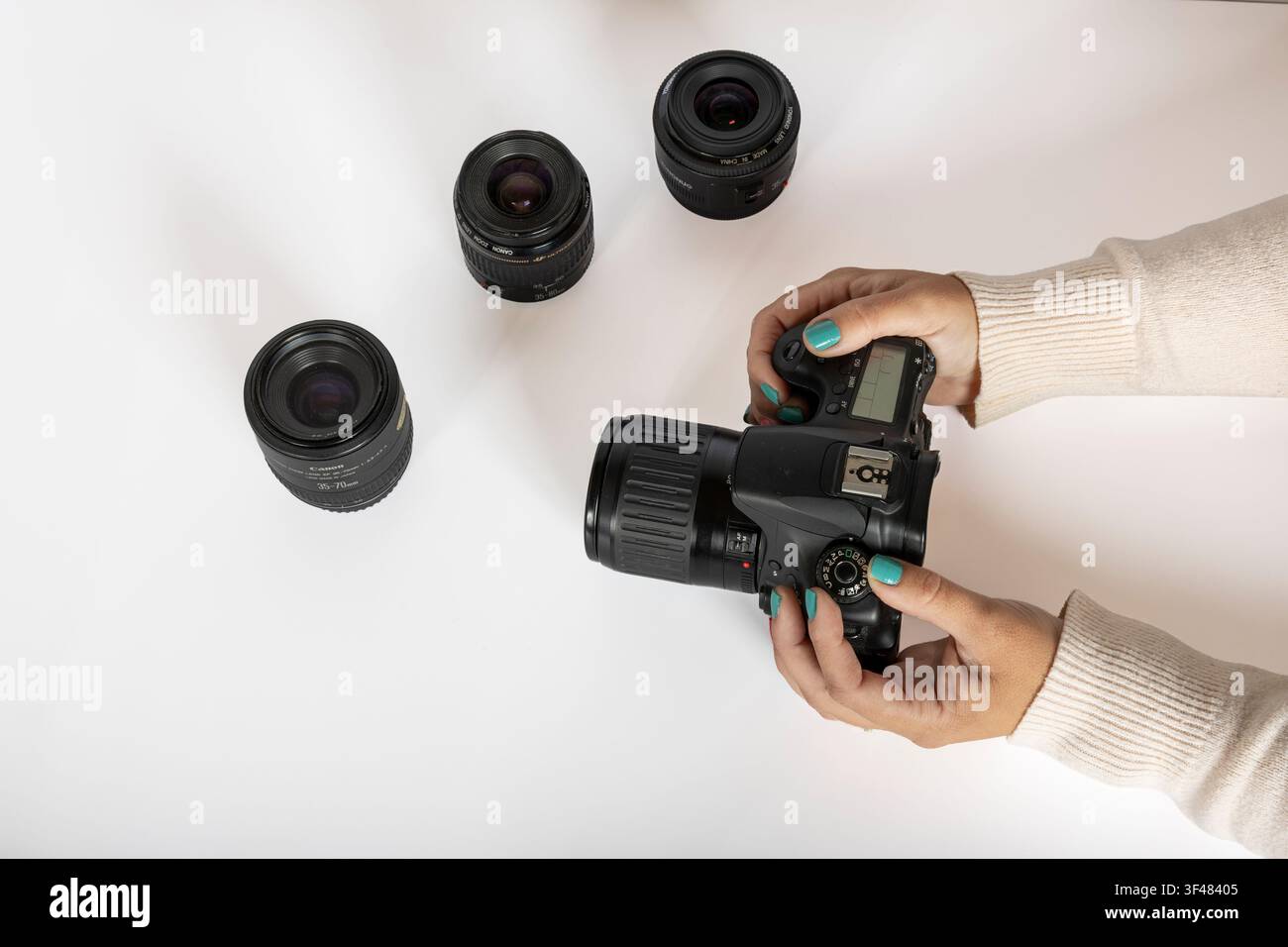 Reviewing DSLR Camera and Interchangeable Lenses on White Surface Stock Photo