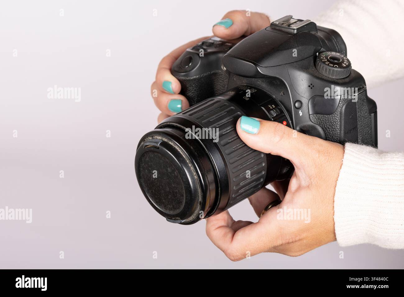 Holding DSLR Camera with Lens Cap Attached Stock Photo