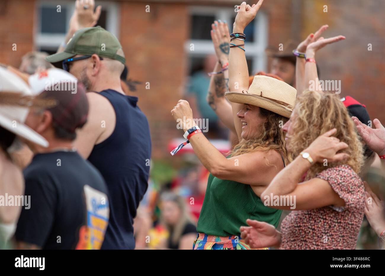 Audience by the main stage waving their arms at the 19th Maverick long weekend Americana music festival held in Easton Farm Park in rural Suffolk. Stock Photo