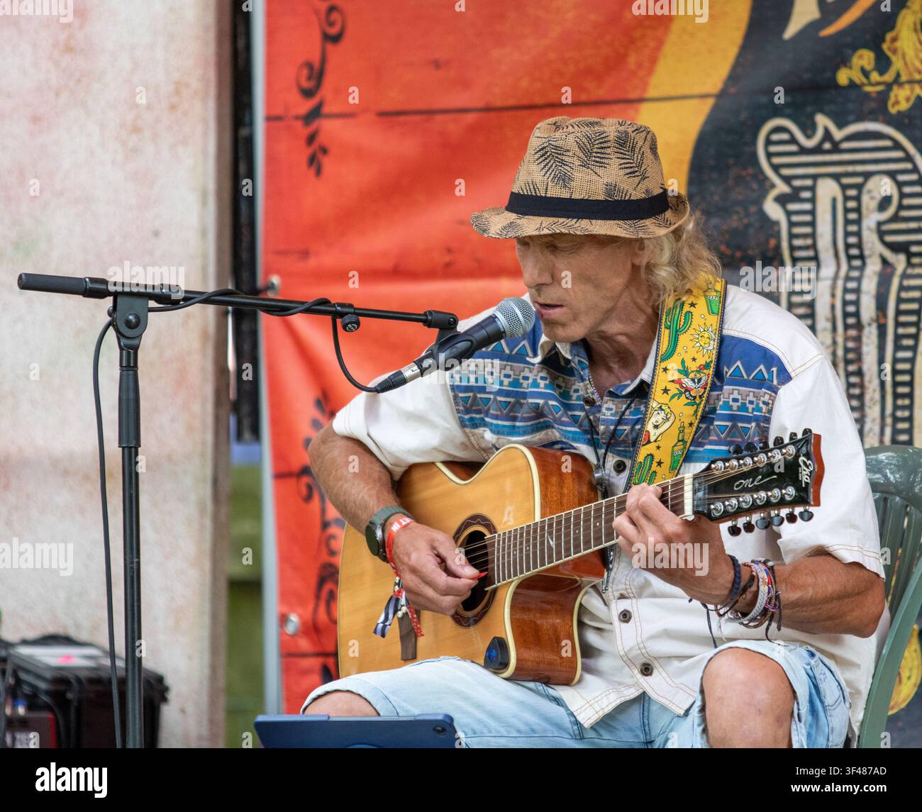 Kev with an acoustic 12 string guitar busking at the 19th Maverick long weekend Americana music festival held in Easton Farm Park in rural Suffolk. Stock Photo