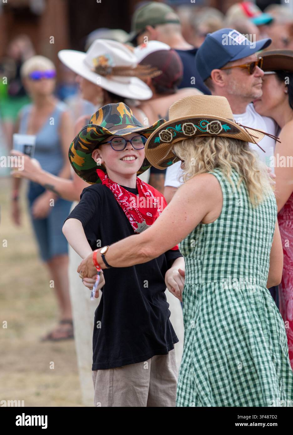 Woman in green gingham and small boy dancing at the 19th Maverick long weekend Americana music festival held in Easton Farm Park in rural Suffolk Stock Photo
