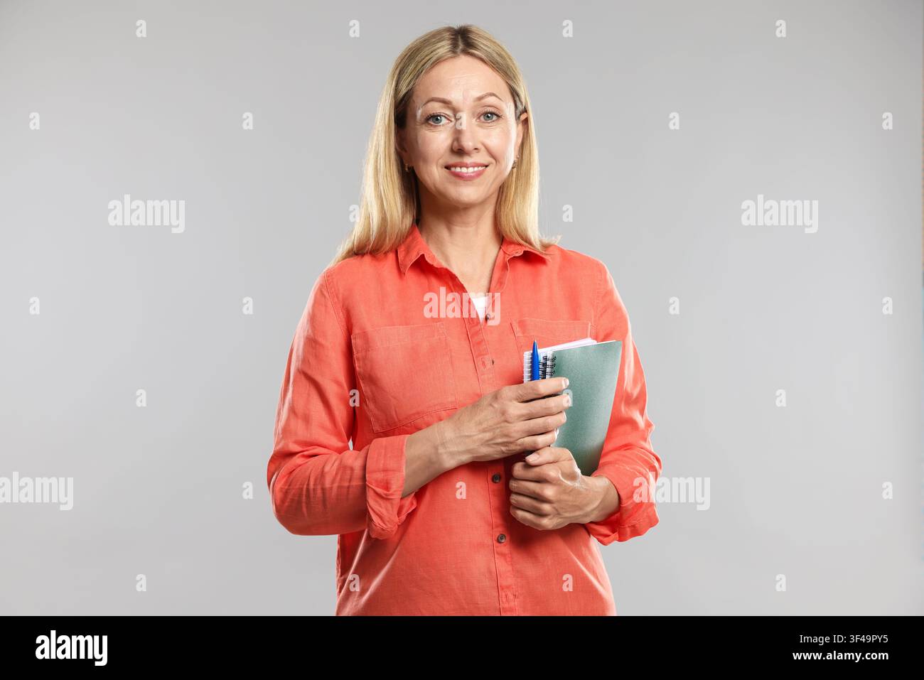 Teacher with notebooks and pen on light grey background Stock Photo