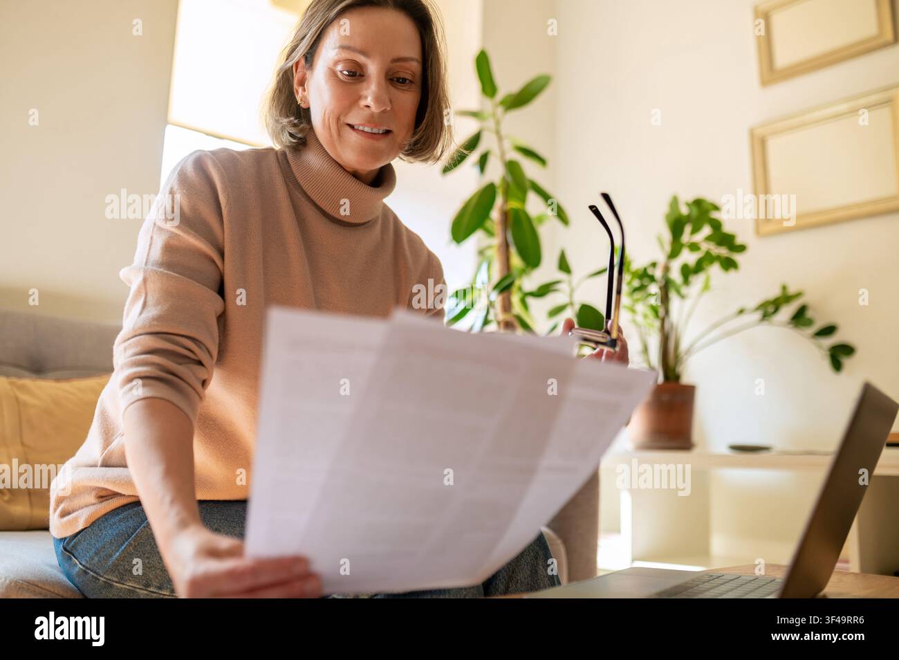 Content middle aged female entrepreneur reading report Stock Photo