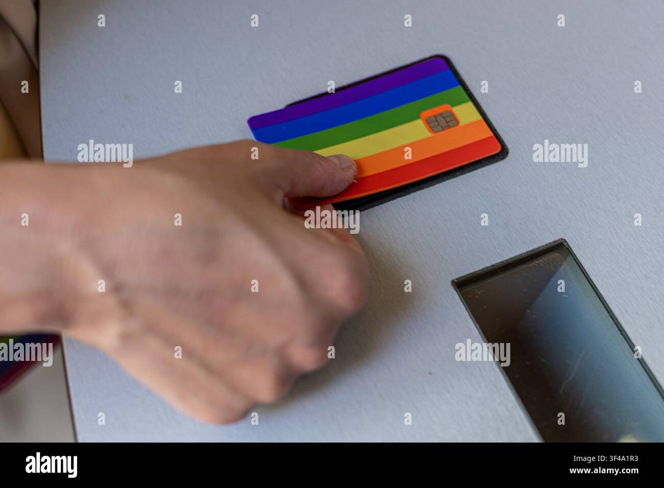 Hand inserting rainbow credit card for lgbtq plus pride payment Stock Photo