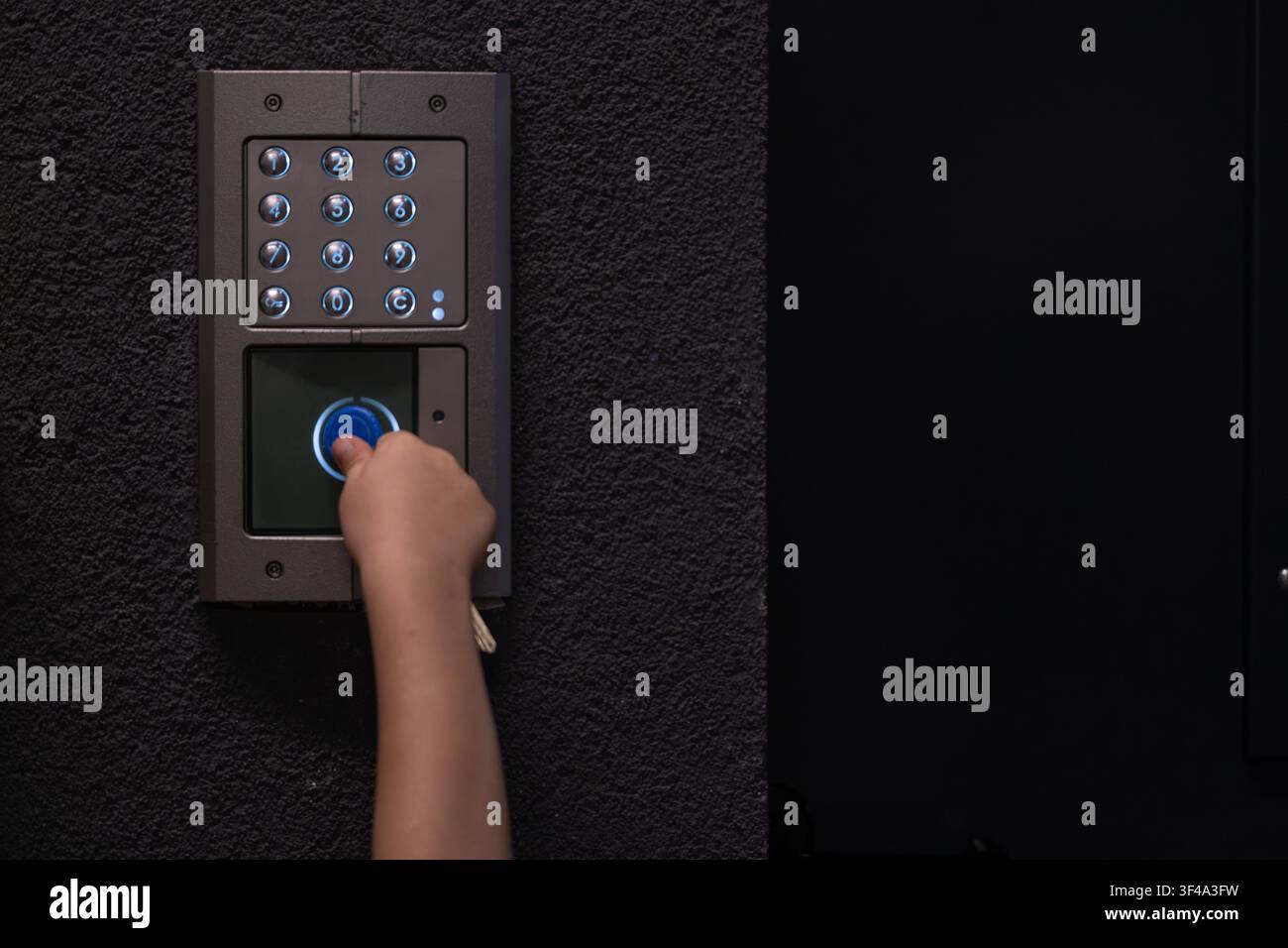 Person using video intercom keypad for secure building access Stock Photo
