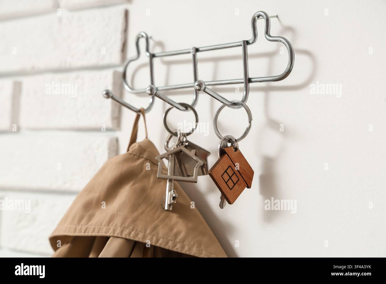 Rack with keys from house on light wall, closeup Stock Photo