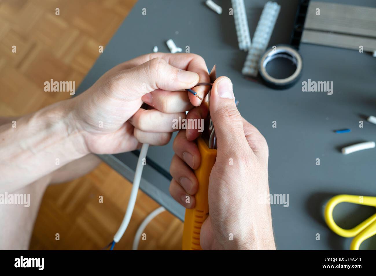 Using a utility knife to prepare cable for a ceiling light installation Stock Photo