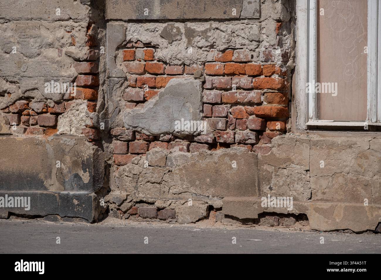 Weathered brick wall with damaged plaster and exposed masonry texture Stock Photo