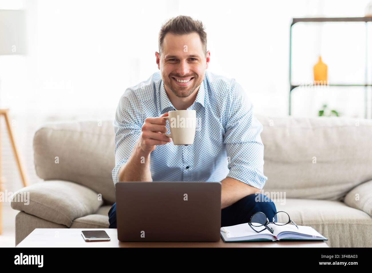 Young man drinking coffee and using laptop Stock Photo