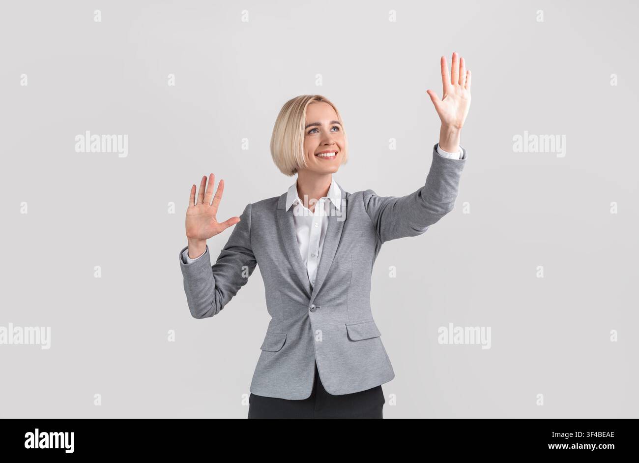 Attractive entrepreneur touching virtual screen on light grey studio background, mockup for design Stock Photo