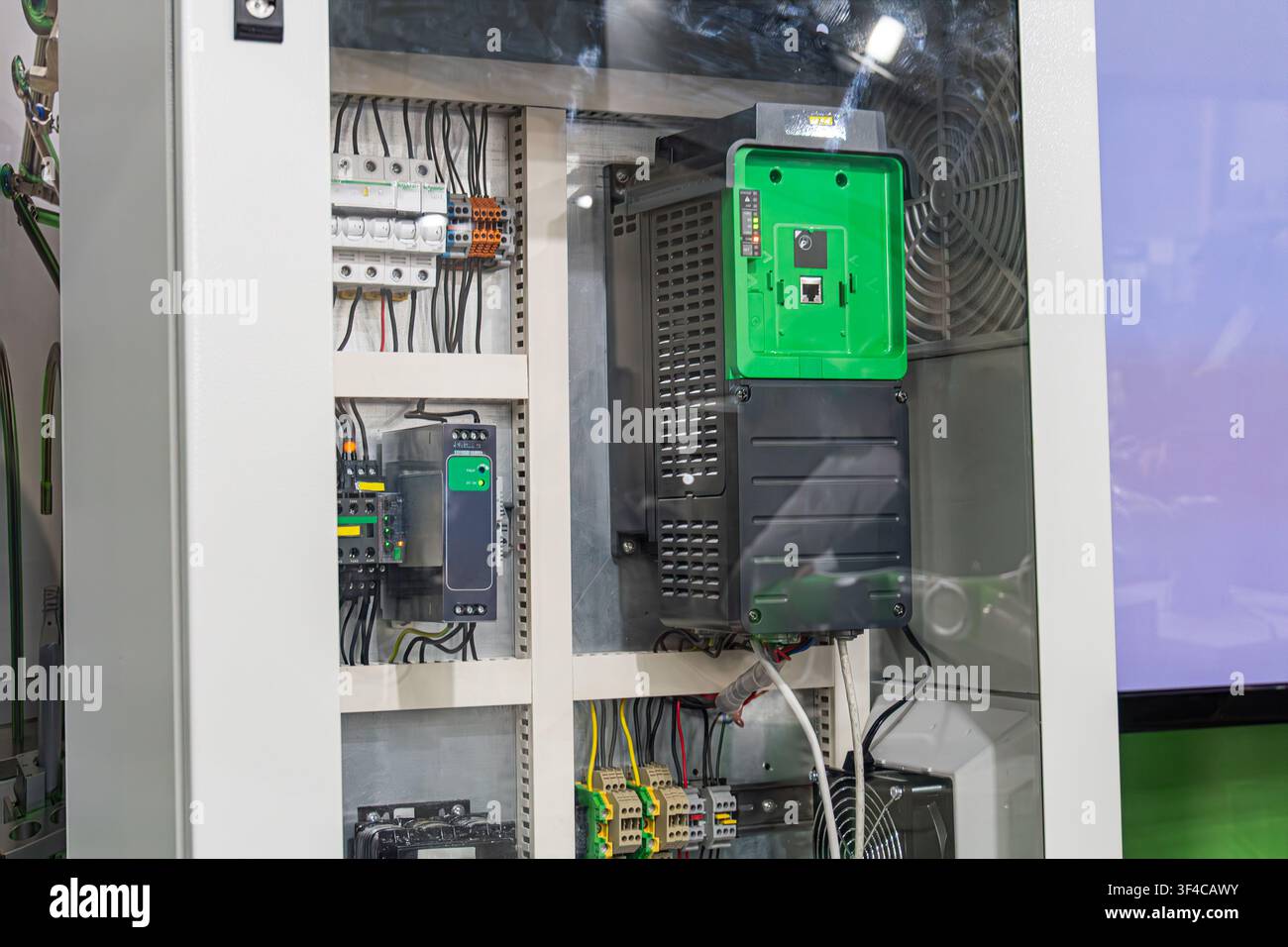 Industrial electrical cabinet featuring a variable frequency drive (VFD) with a green front panel. The enclosure includes circuit breakers, terminal b Stock Photo