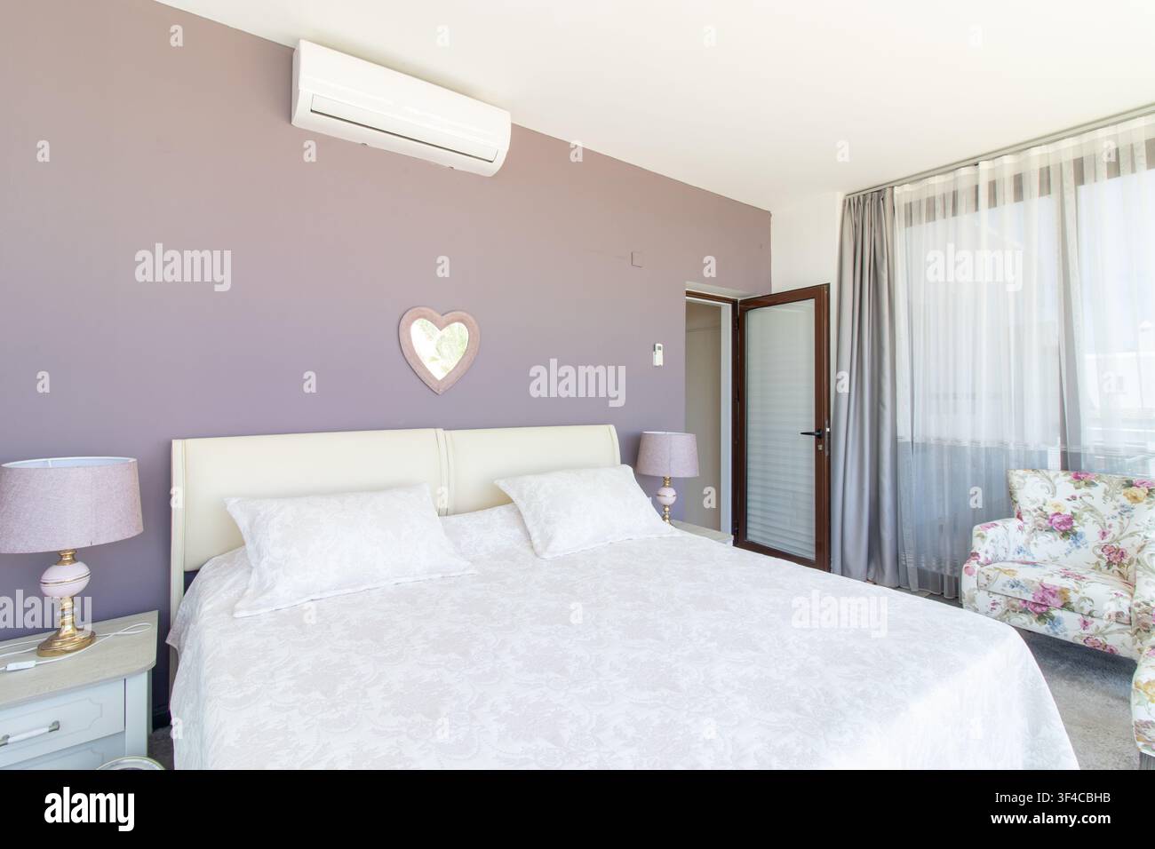 Bright and spacious modern bedroom interior featuring a comfortable double bed Stock Photo