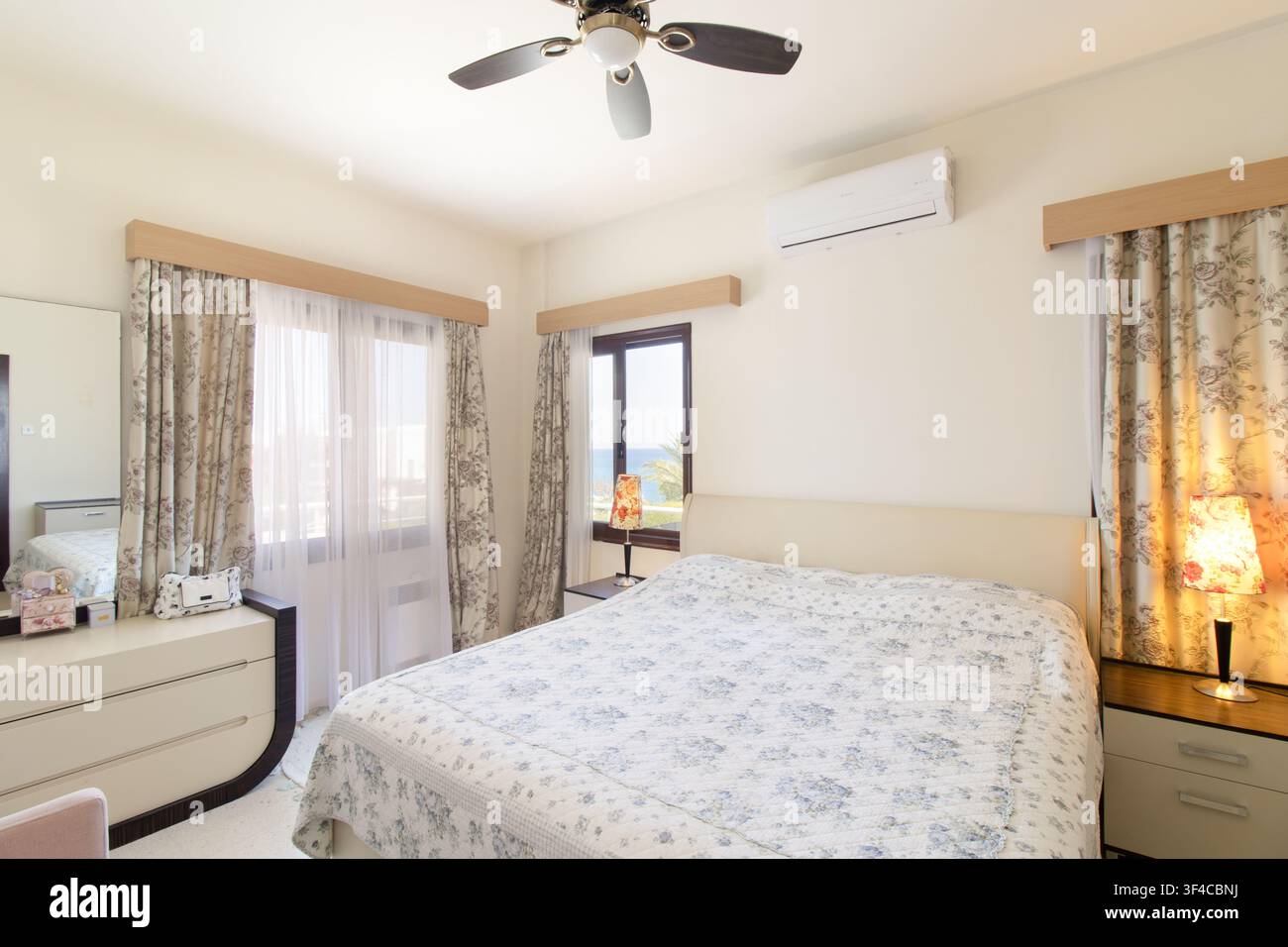 Bright and spacious modern bedroom interior featuring a comfortable double bed Stock Photo