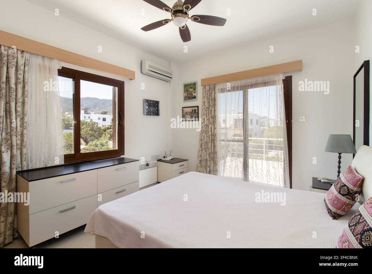 Bright and spacious modern bedroom interior featuring a comfortable double bed Stock Photo