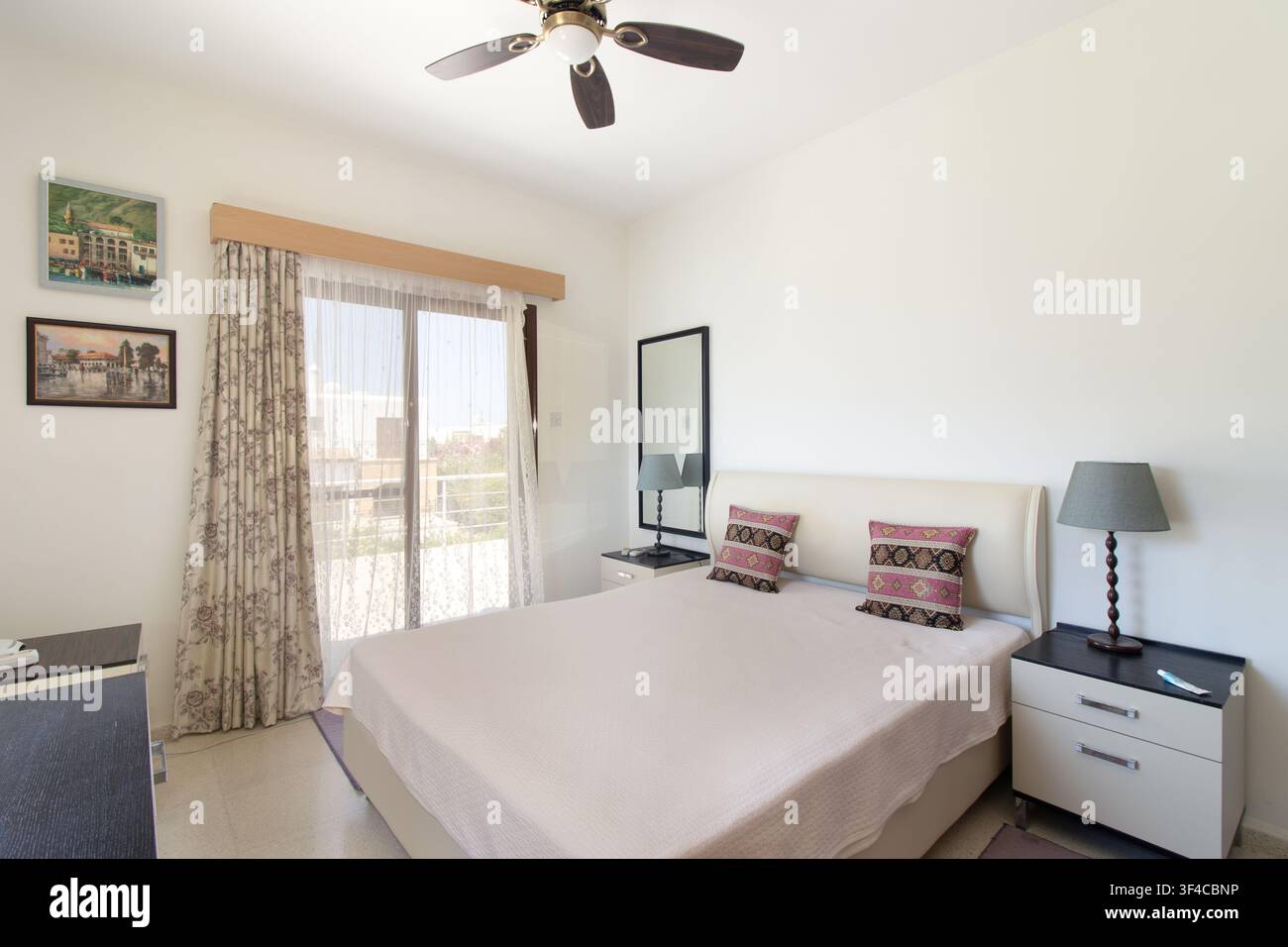 Bright and spacious modern bedroom interior featuring a comfortable double bed Stock Photo