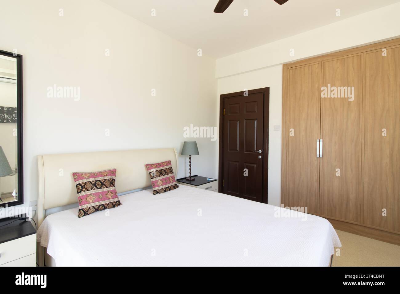 Bright and spacious modern bedroom interior featuring a comfortable double bed Stock Photo